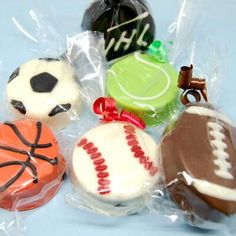 several decorated cookies in plastic wrappers on a blue tablecloth with sports balls and basketballs