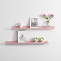 two pink shelves with pictures and vases on them, one has flowers in it