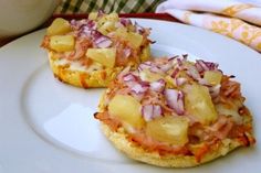 two mini pizzas with pineapple and onions on them sitting on a white plate