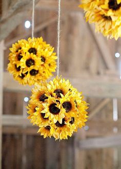 three sunflowers hanging from strings in an old barn with lights on the ceiling