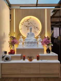 a white buddha statue sitting on top of a wooden table next to vases and flowers