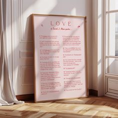 a framed love poem sitting on top of a hard wood floor next to a window