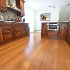 an empty kitchen with wood floors and stainless steel appliances