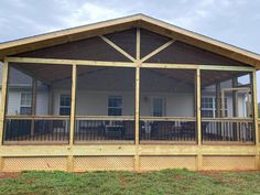 a large screened porch with wooden railings on the front and side of a house