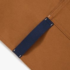 the side view of a brown pants with blue tape on it and an orange pocket