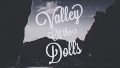 a window with the words valley of the dolls written in white on it and mountains in the background