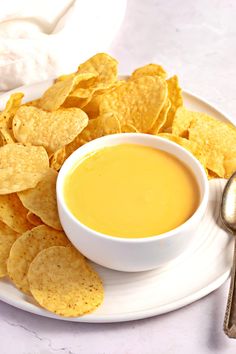 a white plate topped with chips next to a bowl of dip