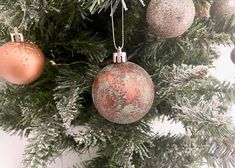 three ornaments hanging from the top of a christmas tree with snow on it's branches