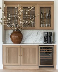 a vase filled with flowers sitting on top of a kitchen counter next to a wine cooler