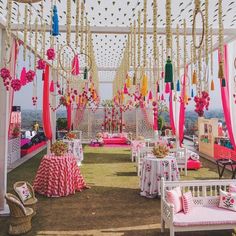 an outdoor wedding venue decorated in pink and white with lots of decorations on the ceiling