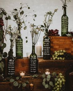 wine bottles with names on them sitting next to candles and flowers