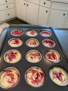 cupcakes with red and white frosting sitting in a muffin tin on top of a counter