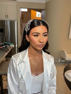 a woman in a white shirt and headband standing next to a kitchen counter top