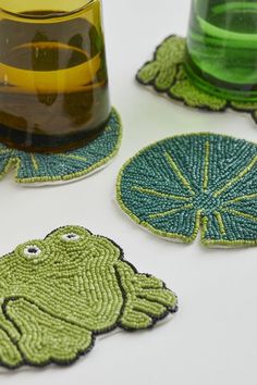 four green coasters with designs on them sitting next to a cup and saucer