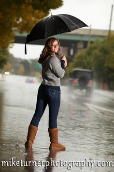 a woman standing in the rain holding an umbrella