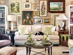 a living room filled with furniture and pictures on the wall above it's coffee table