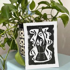 a potted plant sitting on top of a table next to a black and white print