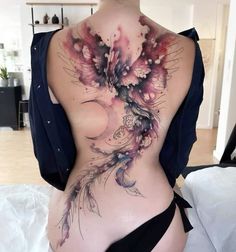 the back of a woman's body is covered in watercolors and feathers