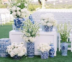 blue and white vases filled with flowers sitting on top of a grass covered field