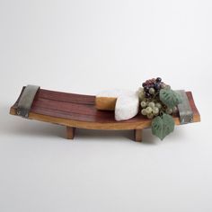 a wooden tray with grapes and cheese on it, sitting on a white table top