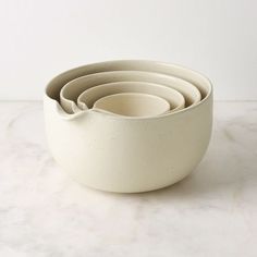 a stack of white bowls sitting on top of a marble counter next to each other