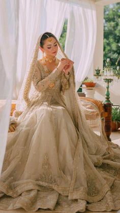 a woman sitting on top of a bed in a wedding dress