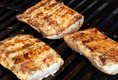 four pieces of meat cooking on a grill