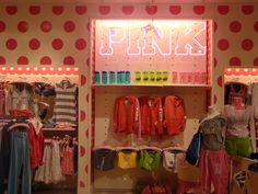 a clothing store with polka dot walls and pink neon signs on the front wall,