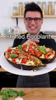 a man holding a plate with food on it and the caption says stuffed eggplant