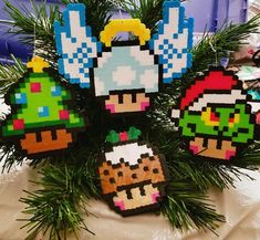 an arrangement of pixel christmas ornaments hanging from a pine tree with other decorations in the background