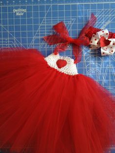 a red tutule and bow laying on a cutting board next to some scissors