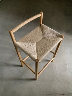 a wooden chair with woven seat and backrests on concrete floored room area