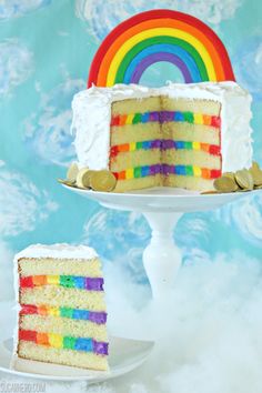 a rainbow cake on a plate with a slice cut out