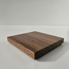 a square wooden object sitting on top of a white table next to a glass bottle