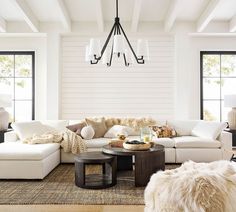 a living room filled with white furniture and lots of natural fur on the rugs