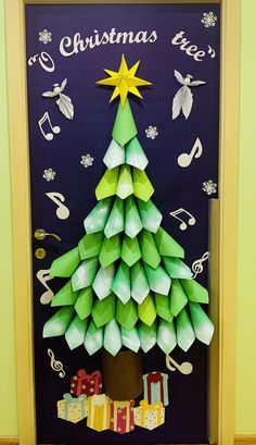 a christmas tree made out of origami on a door with music notes around it