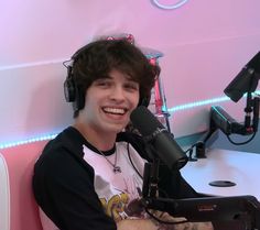 a young man wearing headphones sitting in front of a microphone