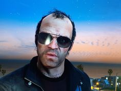 a man with sunglasses on his face standing in front of a cityscape at night