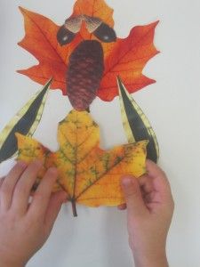 two hands holding up an autumn leaf shaped turkey ornament with leaves on it