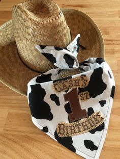 a cow print bandana with the number one on it and a cowboy hat sitting next to it