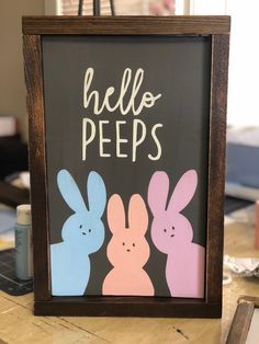 a sign that says hello peeps with some bunnies in front of it on a table