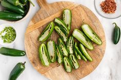 sliced green peppers on a wooden cutting board next to bowls of seasoning and spices