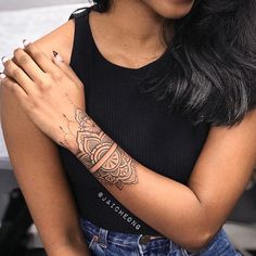 a woman with a tattoo on her arm is smiling at the camera while she holds her hands together