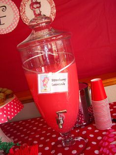 a red drink dispenser sitting on top of a table covered in polka dot paper