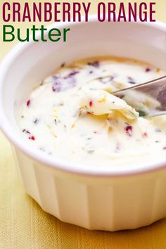 a spoon in a bowl filled with cream cheese and cranberry orange butter sauce