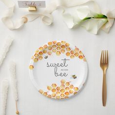 a paper plate with the words sweet as can bee on it next to flowers and gold utensils