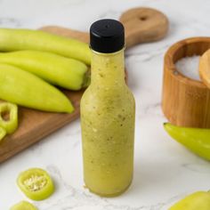 a bottle filled with mustard next to green peppers and jalapenos on a cutting board