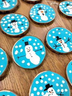 snowman cookies decorated with blue and white frosting on wooden slices, sitting on a table