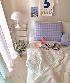 a white bed topped with pillows and blankets next to a table filled with flowers on top of it