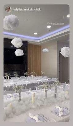 a room filled with tables covered in white linens and clouds floating over the table